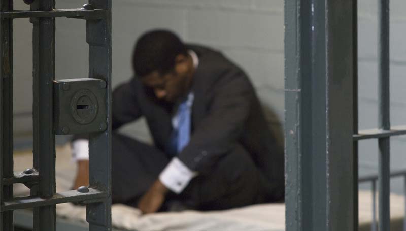 Man sitting in jail cell.